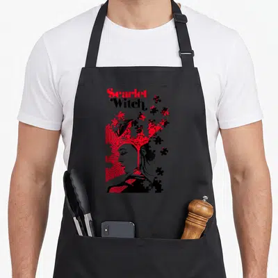 Wanda puzzles lover apron - Scarlet Witch profile dissolving into red and black puzzle pieces with concentric circles — shown on a black cotton canvas apron against a white background