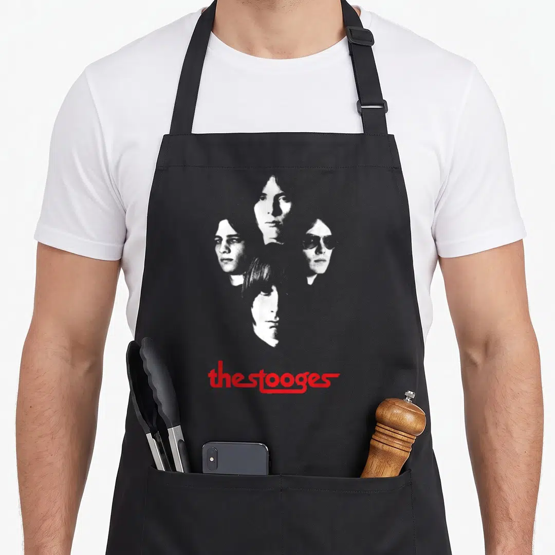 Iggy face apron - four stacked portraits of band members with red the stooges text below — shown on a black cotton canvas apron against a white background