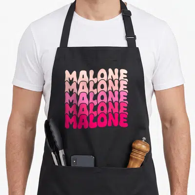 Malone 80s apron - Five stacked lines of Malone text in a pink color gradient — shown on a black cotton canvas apron against a white background