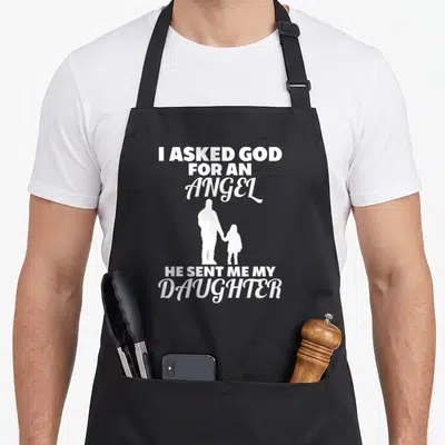 Asked god mom daughter apron - White silhouette of man holding girl's hand flanked by text I Asked God For An Angel He — shown on a black cotton canvas apron against a white background