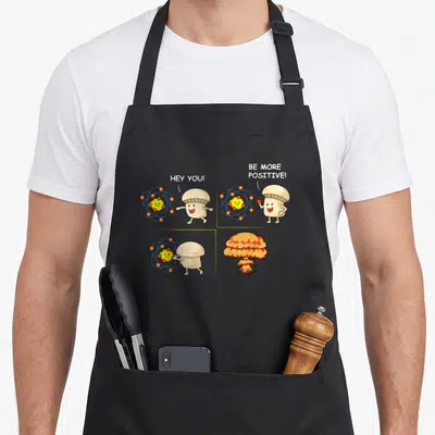 Student science apron - Mushroom character holding atom in four-panel comic ending in explosion with text HEY YOU BE — shown on a black cotton canvas apron against a white background