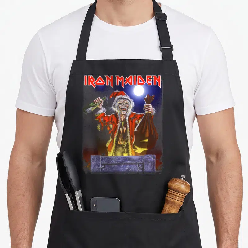 Prayer santa apron - Zombie Santa holding bottle and sack behind stone wall under moon — shown on a black cotton canvas apron against a white background
