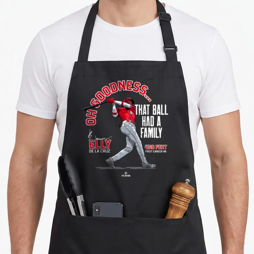 Ball family aprons - Elly De La Cruz swinging bat with OH GOODNESS THAT BALL HAD A FAMILY text in red and white — shown on a black cotton canvas apron against a white background