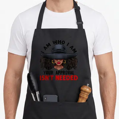 Curly african american aprons - Cartoon woman in wide hat with I AM WHO I AM YOUR APPROVAL ISN'T NEEDED text — shown on a black cotton canvas apron against a white background