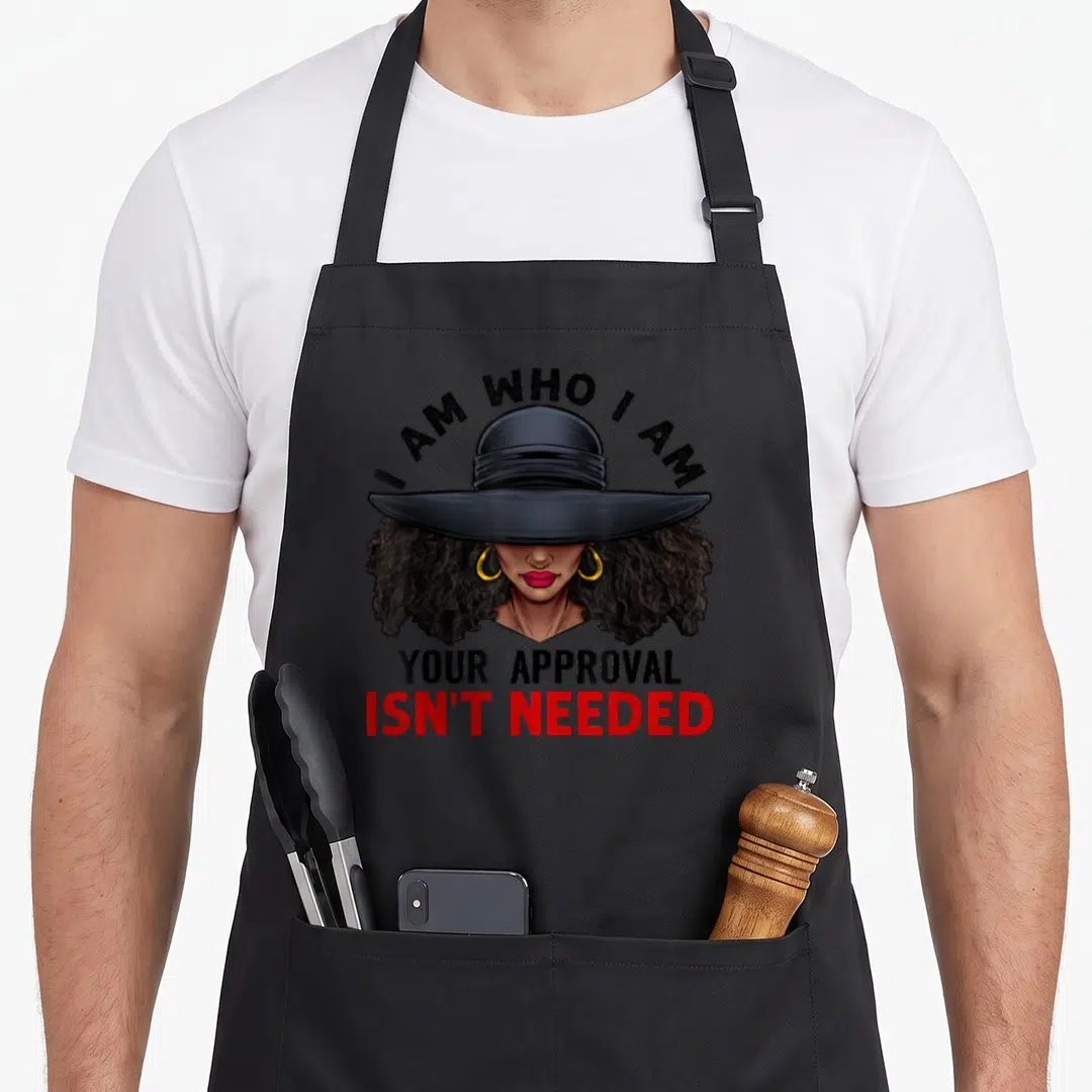 Curly african american aprons - Cartoon woman in wide hat with I AM WHO I AM YOUR APPROVAL ISN'T NEEDED text — shown on a black cotton canvas apron against a white background