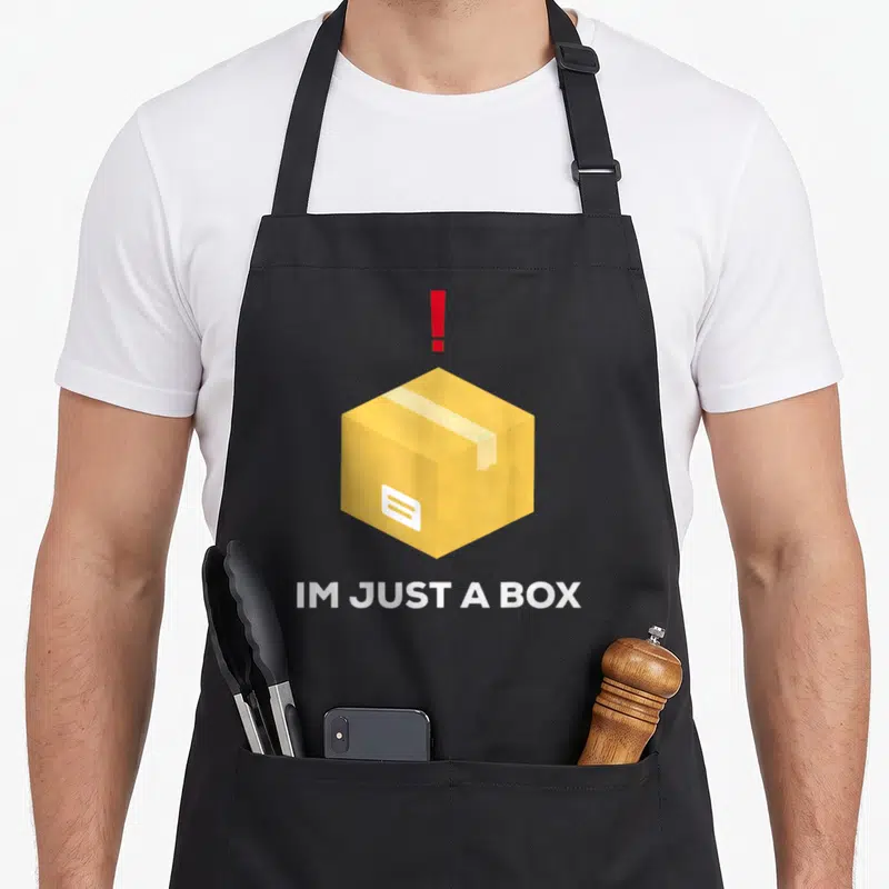 Fast box apron - Yellow cardboard box with red exclamation mark and white text IM JUST A BOX — shown on a black cotton canvas apron against a white background