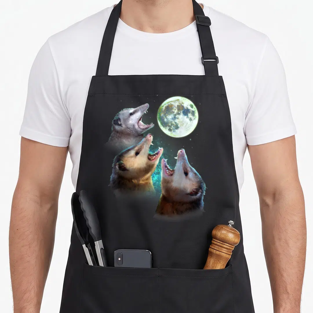 Three moon funny apron - Three realistic opossums howling at a full moon in grey and blue — shown on a black cotton canvas apron against a white background