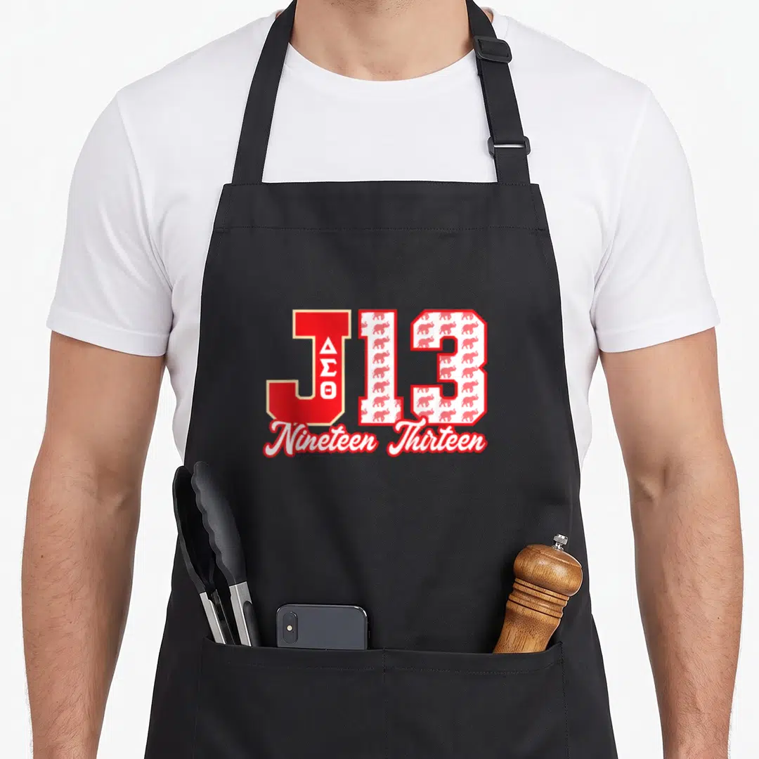 Sigma straight life apron - Red J with stacked Greek letters beside white 13 filled with elephant pattern and Nineteen — shown on a black cotton canvas apron against a white background
