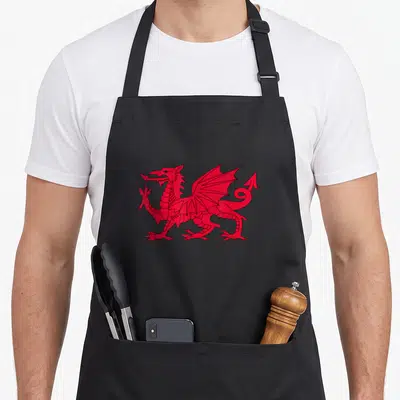 Dragon wale welsh apron - Single red dragon in black line art, centered on apron front — shown on a black cotton canvas apron against a white background