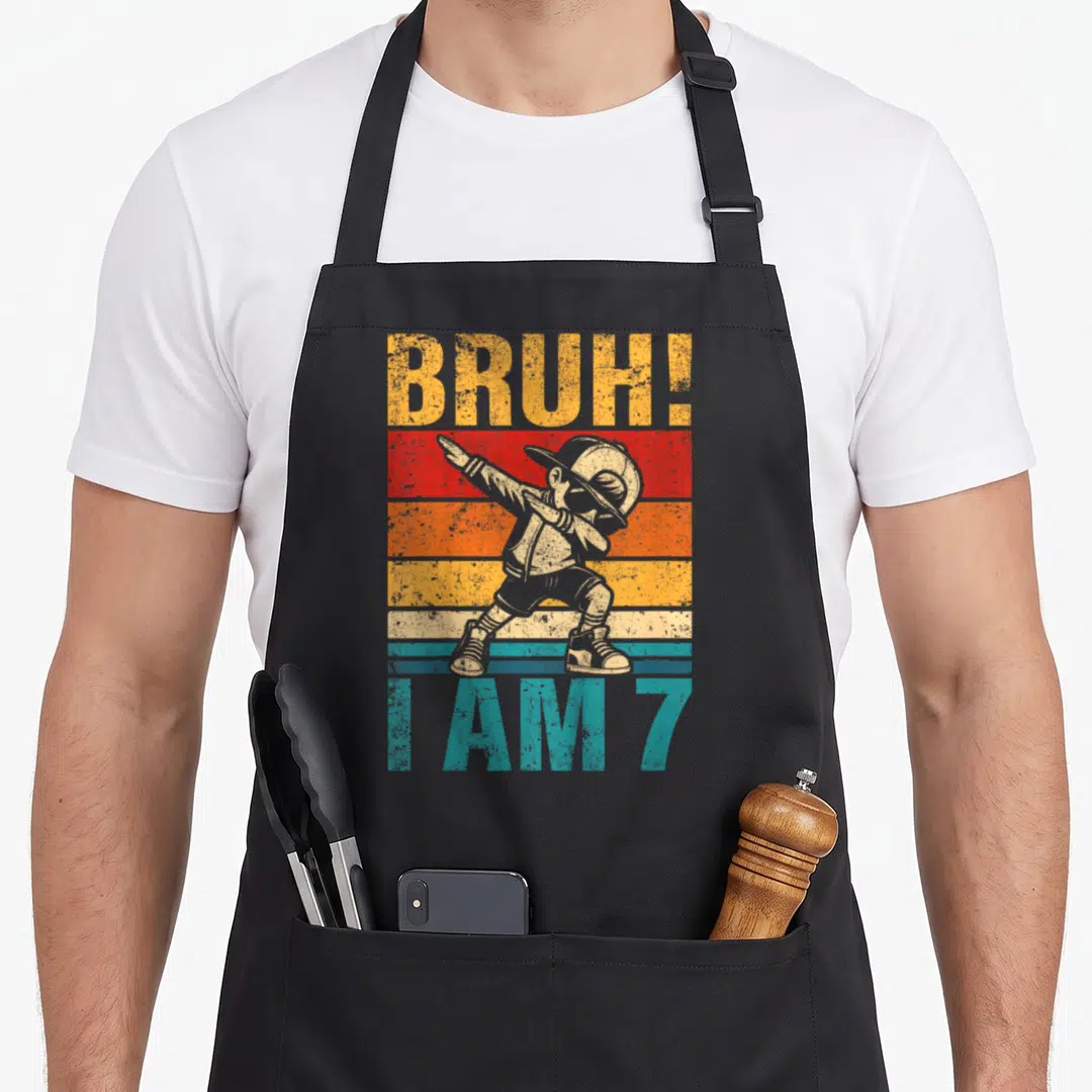 Dabbing bruh birthday apron - Boy dabbing over yellow red orange blue grey stripes with text BRUH! and I AM 7 — shown on a black cotton canvas apron against a white background