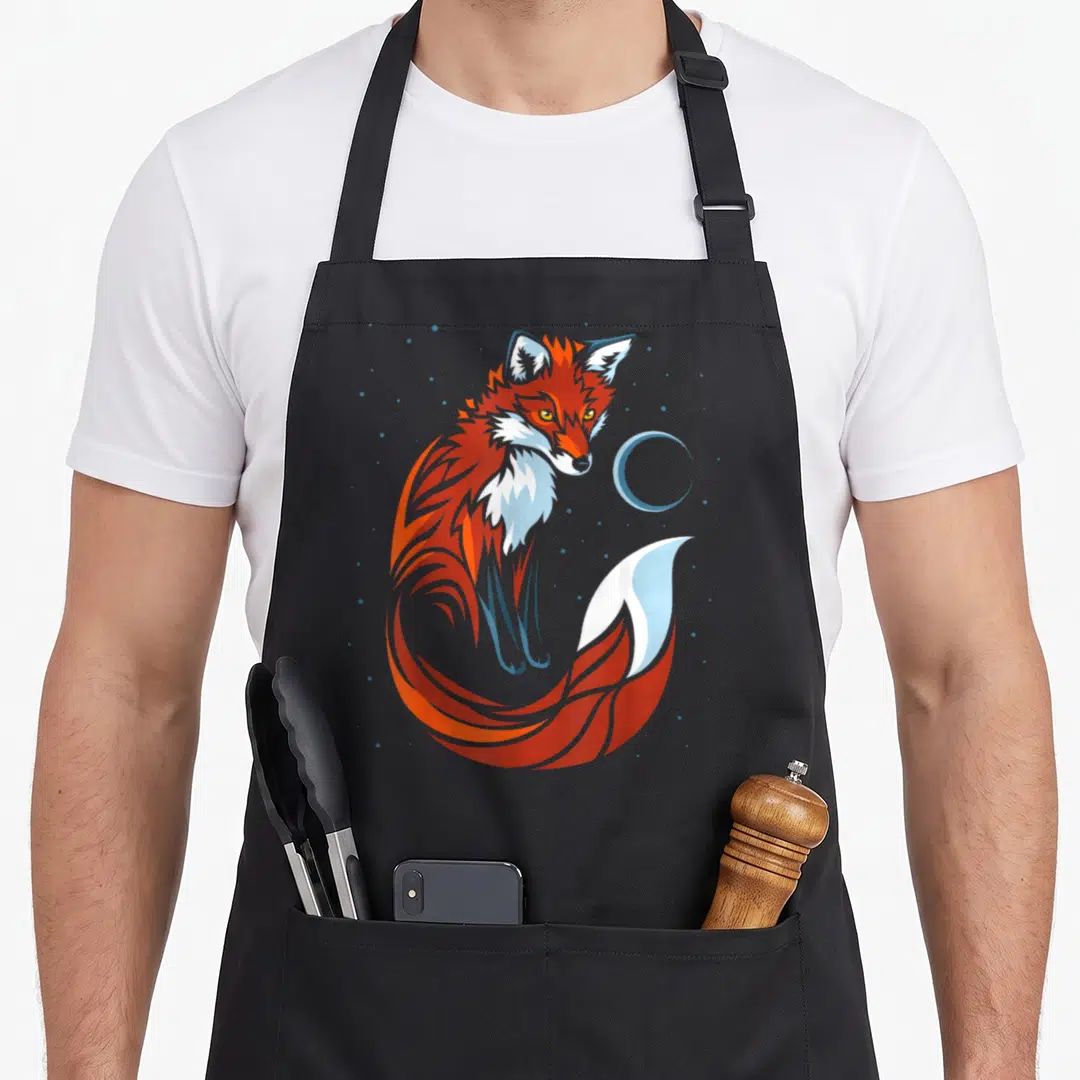 Tribal fox print apron - Stylized orange and red fox with light blue moon and scattered blue dots in cartoon style — shown on a black cotton canvas apron against a white background