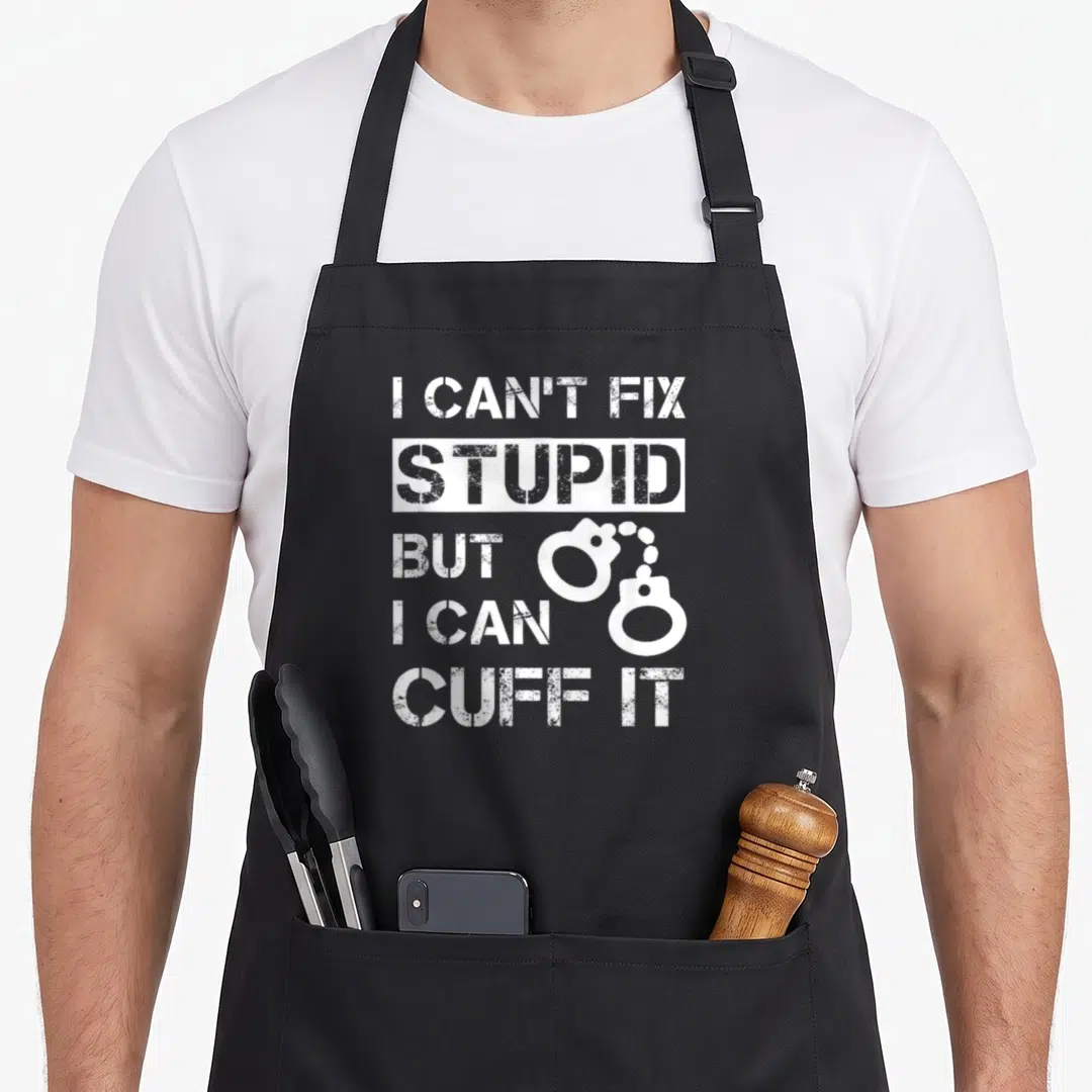 Fix stupid aprons - White distressed stencil text I CAN'T FIX STUPID BUT I CAN CUFF IT with a pair of handcuffs graphic — shown on a black cotton canvas apron against a white background