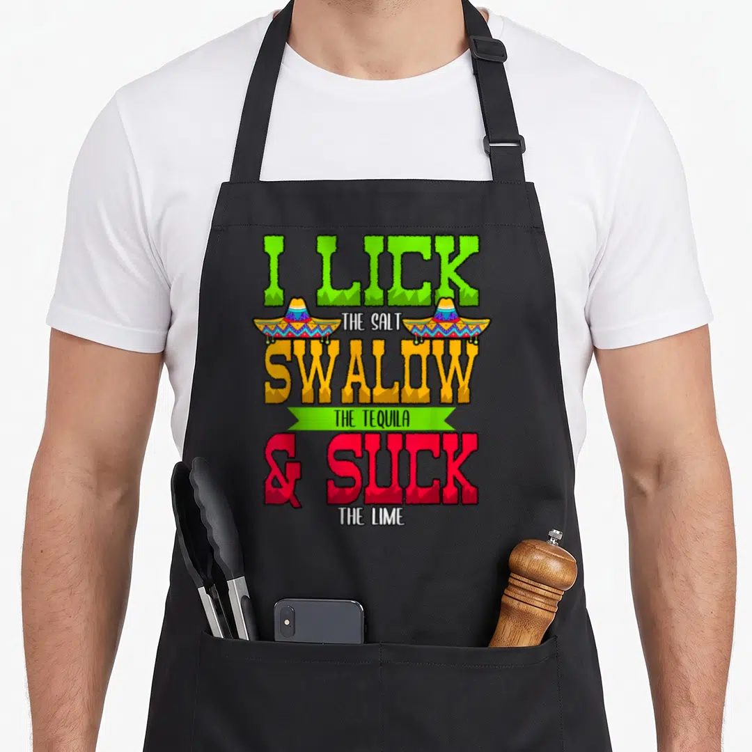 Lick i love tequila apron - Stacked text I LICK THE SALT SWALLOW THE TEQUILA & SUCK THE LIME with two sombreros — shown on a black cotton canvas apron against a white background