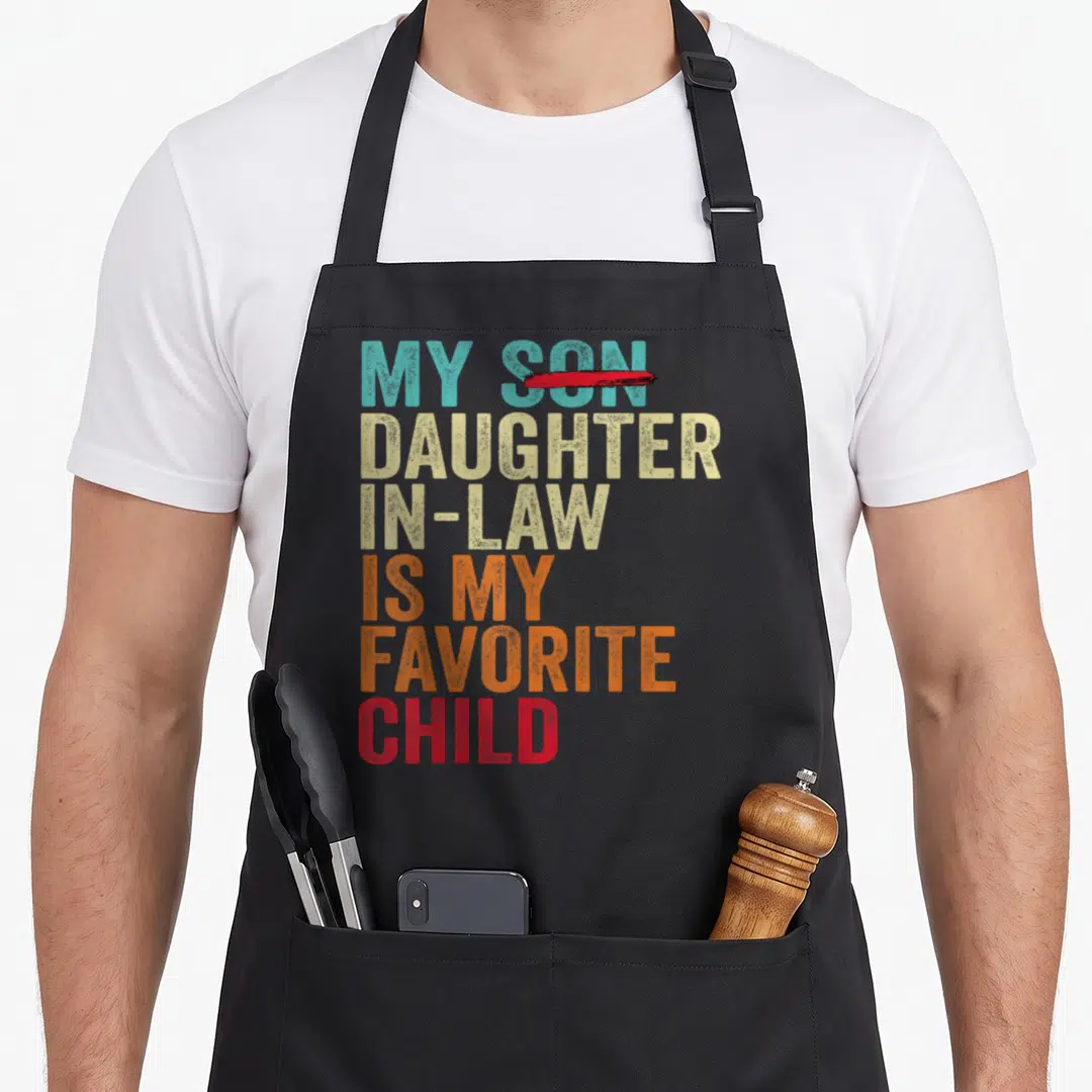 Son mom and daughter aprons - My Daughter In Law Is My Favorite Child text with crossed out Son in teal beige orange red — shown on a black cotton canvas apron against a white background