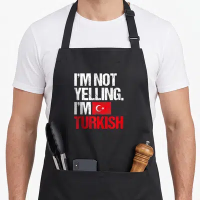Yelling turkey apron - Distressed white and red text I'm Not Yelling I'm Turkish with flag graphic — shown on a black cotton canvas apron against a white background