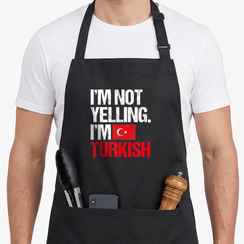 Yelling turkey apron - Distressed white and red text I'm Not Yelling I'm Turkish with flag graphic — shown on a black cotton canvas apron against a white background