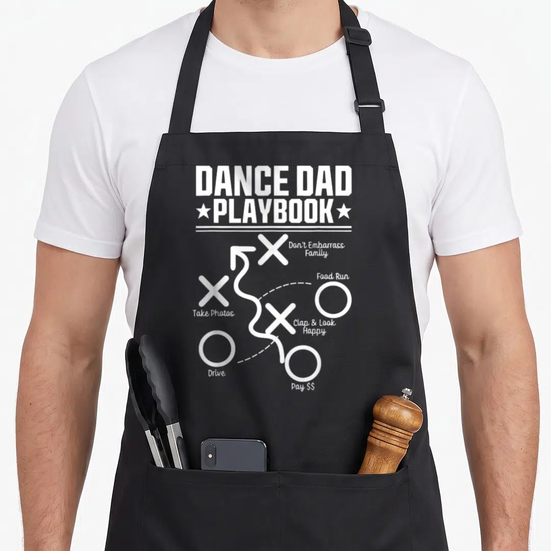 Comp daddy apron - White playbook diagram with Xs Os arrows and text labels for dance dad tasks — shown on a black cotton canvas apron against a white background