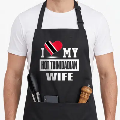 Trinidadian wife apron - I MY HOT TRINIDADIAN WIFE text with red black white heart on black apron — shown on a black cotton canvas apron against a white background