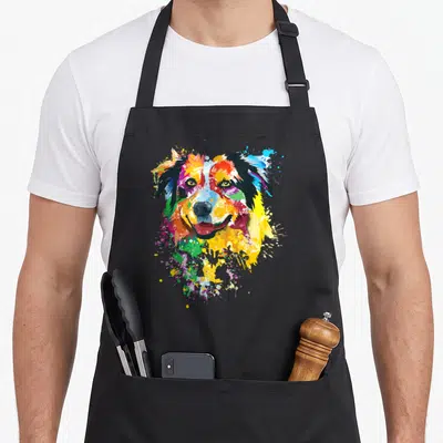 Shepherd aussie australian aprons - Multicolored watercolor dog head surrounded by red, yellow, blue, green, and orange — shown on a black cotton canvas apron against a white background