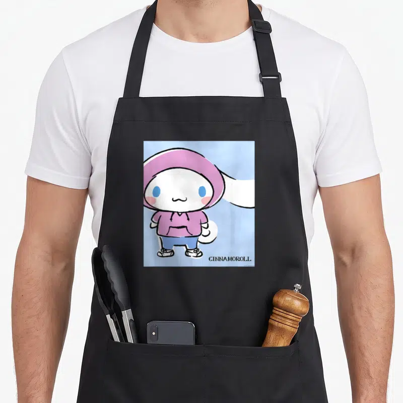Collection streetwear apron - Cinnamoroll in purple hoodie on light blue with GINNAMOROLL text at bottom right — shown on a black cotton canvas apron against a white background
