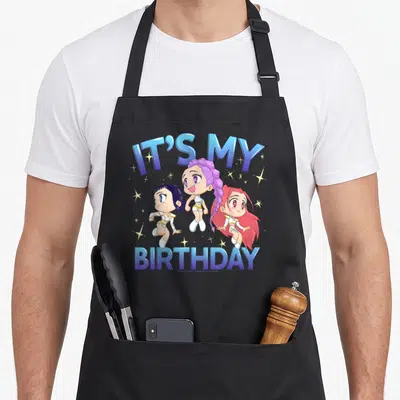 Chibi birthday apron - Three chibi girls surrounded by stars with It's My Birthday text in blue and purple — shown on a black cotton canvas apron against a white background
