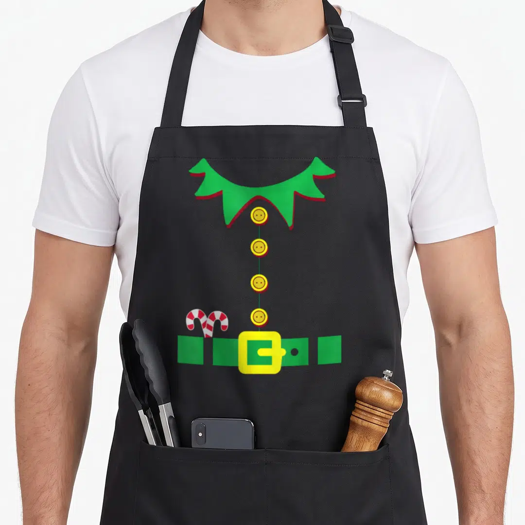 Costume elf apron - Green jagged collar, four yellow buttons, green belt, and red white candy cane — shown on a black cotton canvas apron against a white background