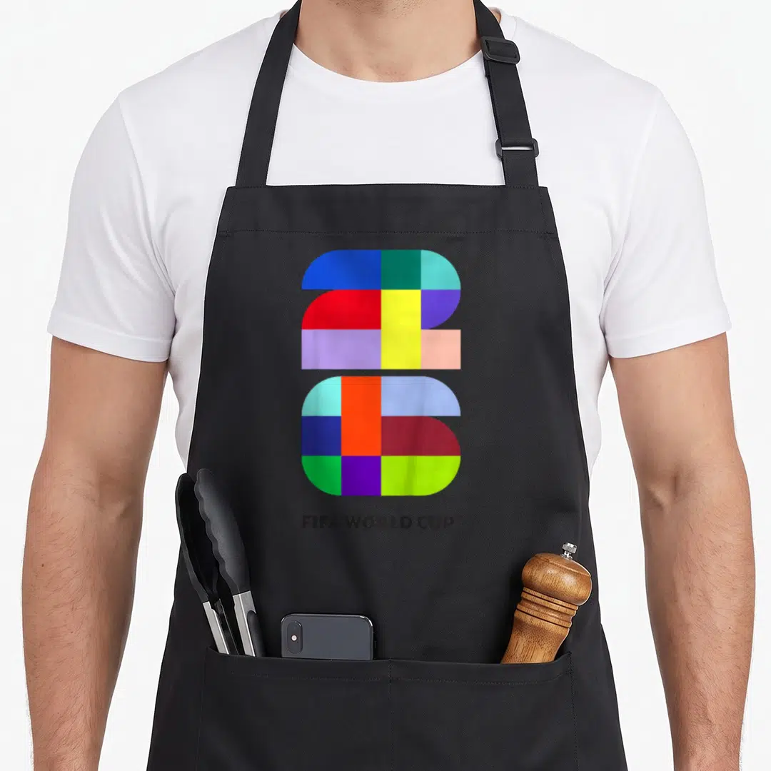 Fifa grade soccer apron - Multicolored geometric 26 graphic with FIFA WORLD CUP text in blue red yellow green purple — shown on a black cotton canvas apron against a white background