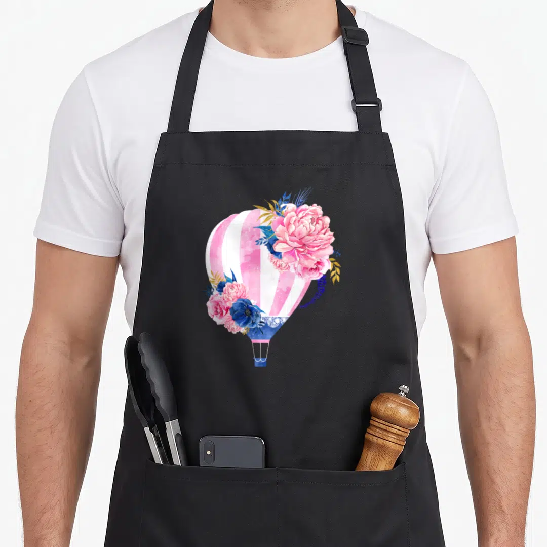 Beautiful balloon apron - Pink white striped hot air balloon with blue and pink watercolor flowers and yellow leaves — shown on a black cotton canvas apron against a white background