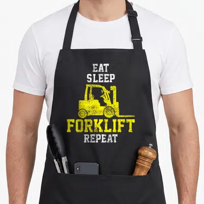 Forklift construction apron - Yellow forklift silhouette between white eat sleep and yellow forklift repeat text — shown on a black cotton canvas apron against a white background