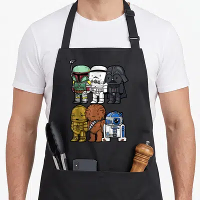 Trooper boba apron - Six chibi Star Wars characters in two rows of three wearing white, black, brown, gold, and green — shown on a black cotton canvas apron against a white background