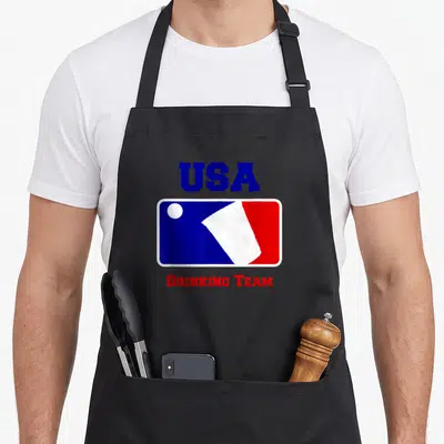 Game beer pong apron - Blue USA text above rectangular logo with white ball and red white section, red DRINKING TEAM — shown on a black cotton canvas apron against a white background