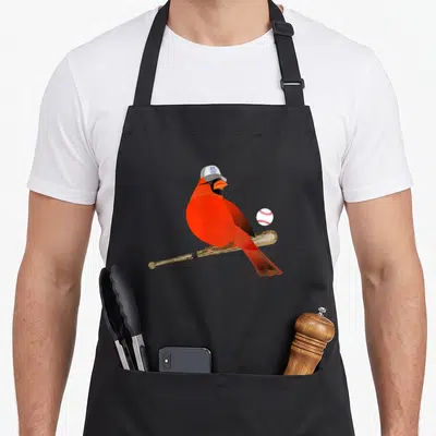 Saint cardinal apron - Red cardinal on tan bat wearing St Louis cap next to white baseball — shown on a black cotton canvas apron against a white background