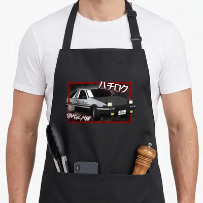 Drift car apron - Cartoon black and white car with red border and Japanese text — shown on a black cotton canvas apron against a white background