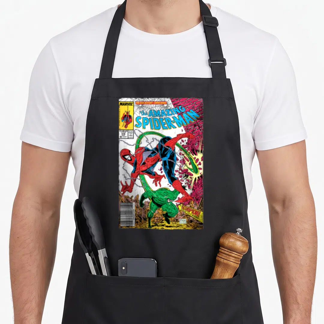 Comic scorpion apron - Vintage Spider-Man leaping over green Scorpion on brick wall with Marvel logo and price box — shown on a black cotton canvas apron against a white background