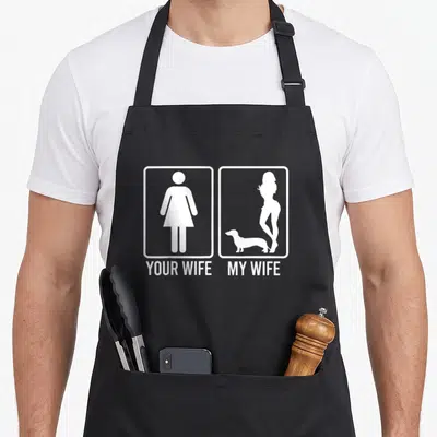 Dachshund personalized dog apron - White YOUR WIFE MY WIFE text with dachshund silhouette next to generic female symbol — shown on a black cotton canvas apron against a white background