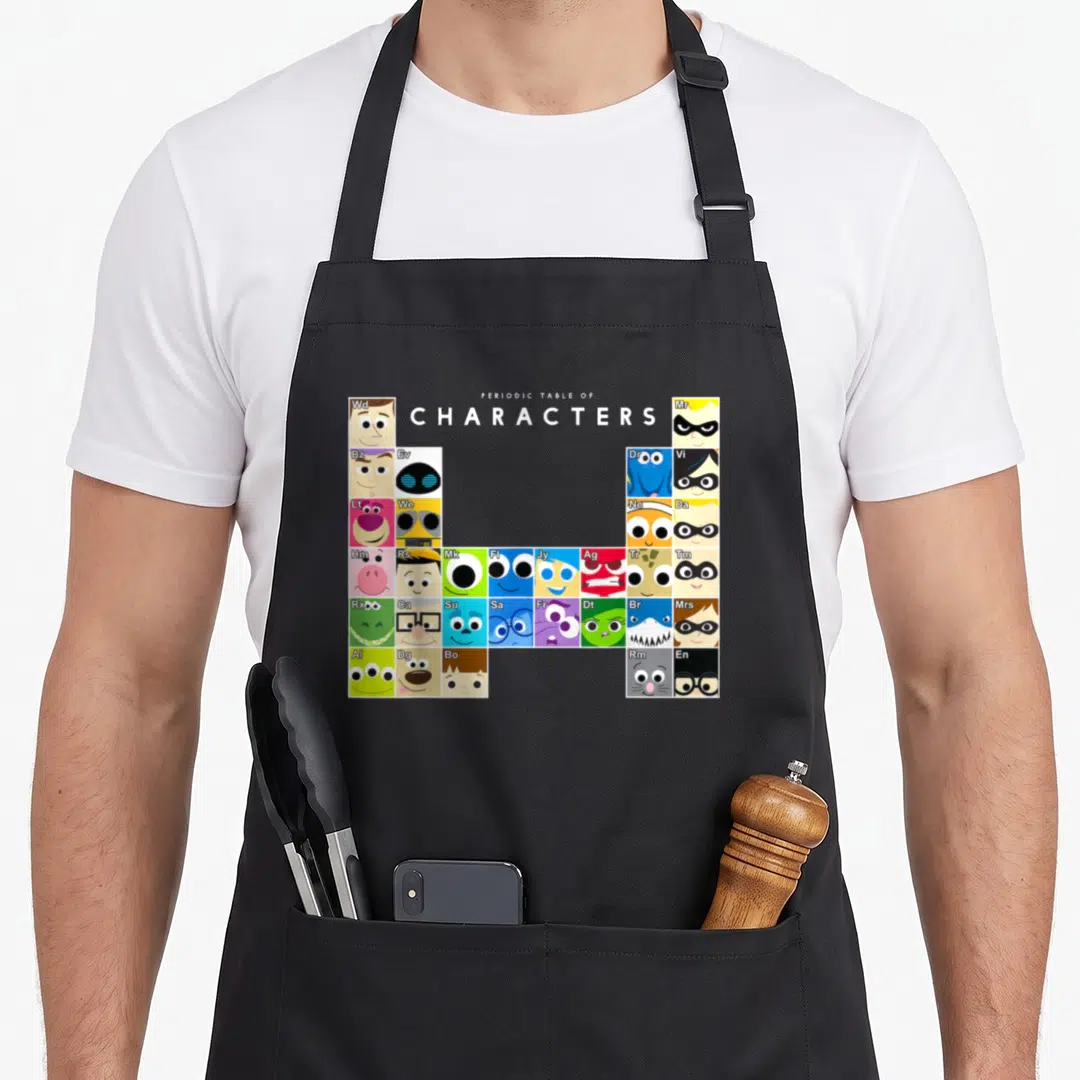 Collection table apron - Grid of colorful character faces with two-letter symbols arranged under centered text — shown on a black cotton canvas apron against a white background