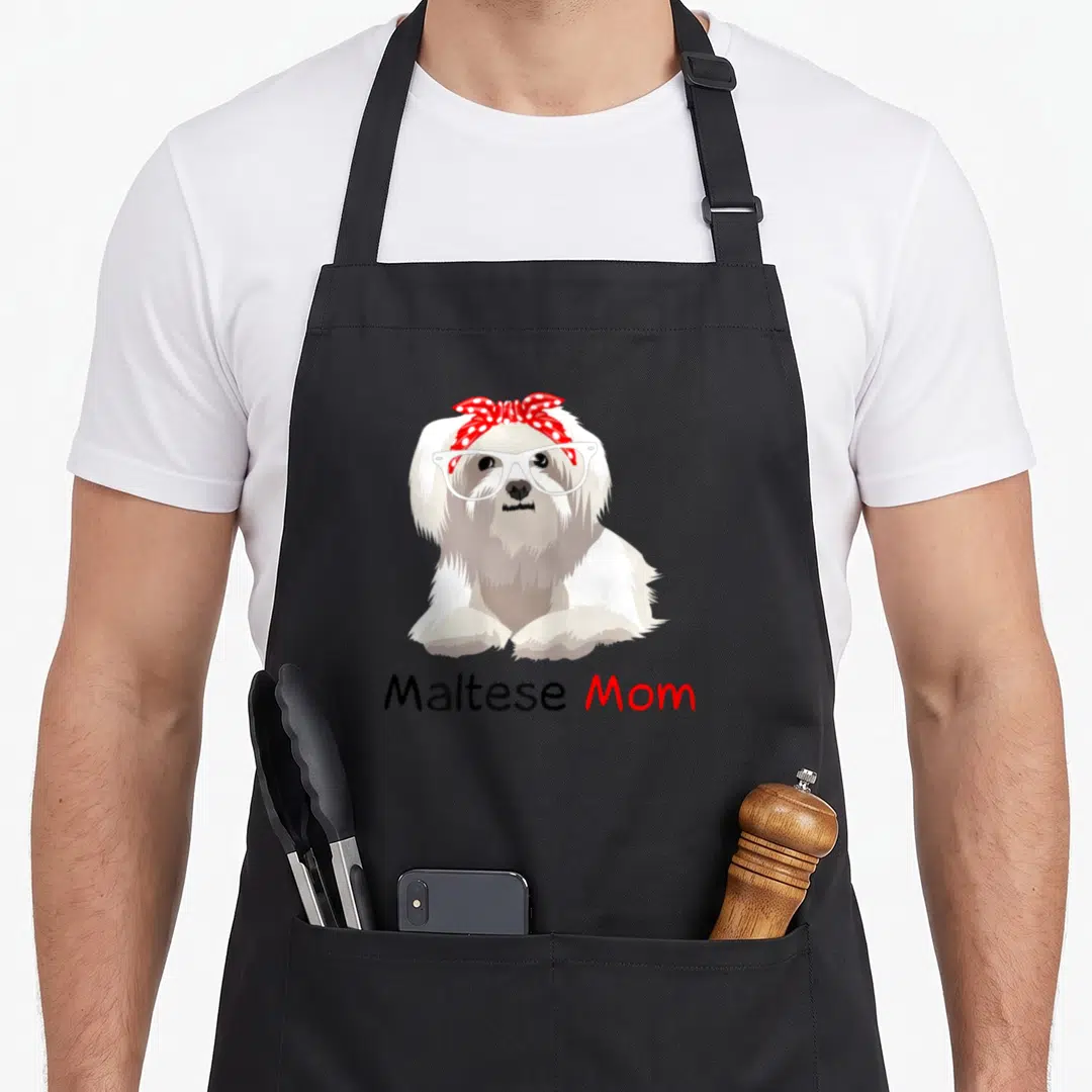 Maltese bandana dog apron - White Maltese dog wearing glasses and red polka dot bandana with text below — shown on a black cotton canvas apron against a white background