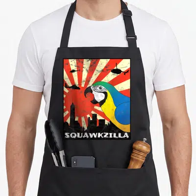 Squawk kawaii apron - Retro macaw head with SQUAWKZILLA text, red sun stripes, and three helicopters over city skyline — shown on a black cotton canvas apron against a white background