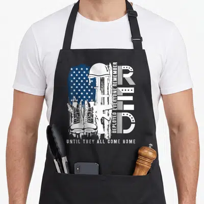Flag military apron - Distressed white helmet rifle boots USA flag stars DEPLOYED EVERYONE REMEMBER UNTIL THEY ALL COME — shown on a black cotton canvas apron against a white background
