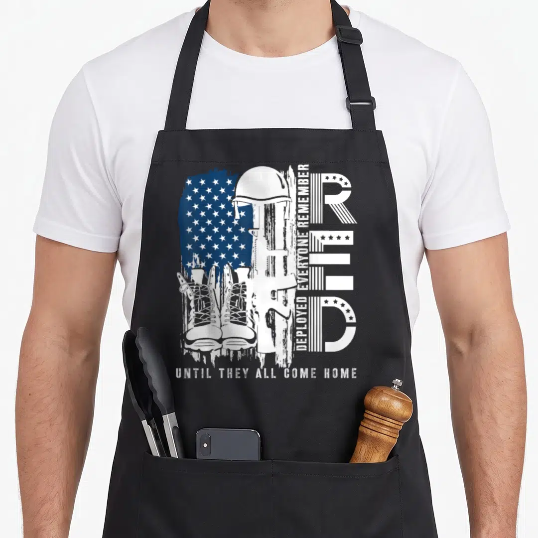 Flag military apron - Distressed white helmet rifle boots USA flag stars DEPLOYED EVERYONE REMEMBER UNTIL THEY ALL COME — shown on a black cotton canvas apron against a white background