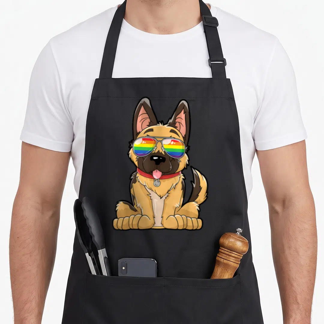 German shepherd gay pride apron - Cartoon tan and black German Shepherd puppy wearing rainbow sunglasses and red collar — shown on a black cotton canvas apron against a white background