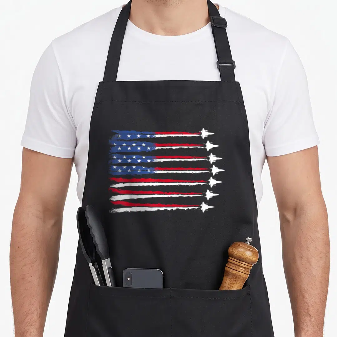 Blue patriotic apron - Eight white fighter jets flying right, contrails form distressed red white blue flag with stars — shown on a black cotton canvas apron against a white background