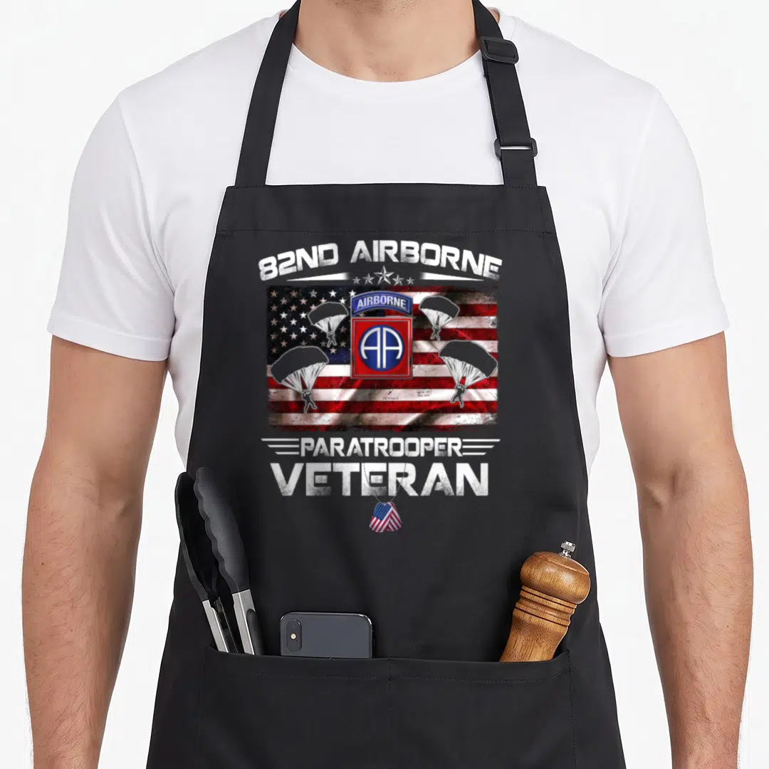 Flag paratrooper apron - 82nd Airborne text over USA flag with three parachutes and veteran dog tag in distressed red — shown on a black cotton canvas apron against a white background
