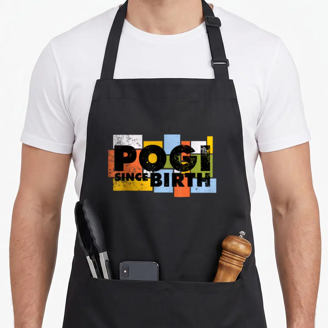 Pogi special edition apron - POGI SINCE BIRTH text over yellow blue red white and green rectangles — shown on a black cotton canvas apron against a white background