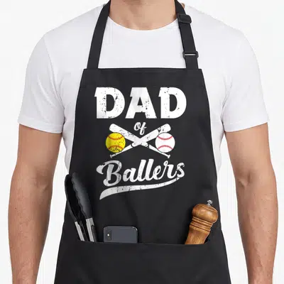 Softball player baseball apron - Dad of Ballers text with crossed bats and yellow and white balls — shown on a black cotton canvas apron against a white background