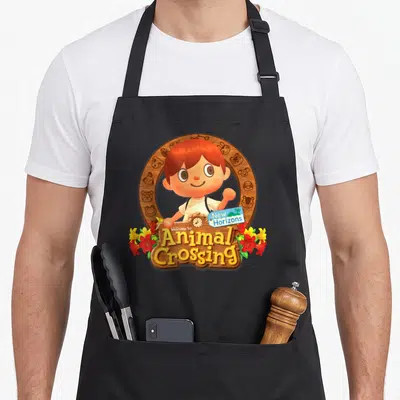 Fall animal apron - Waving cartoon person in circular wooden frame with Welcome to Animal Crossing New Horizons text — shown on a black cotton canvas apron against a white background