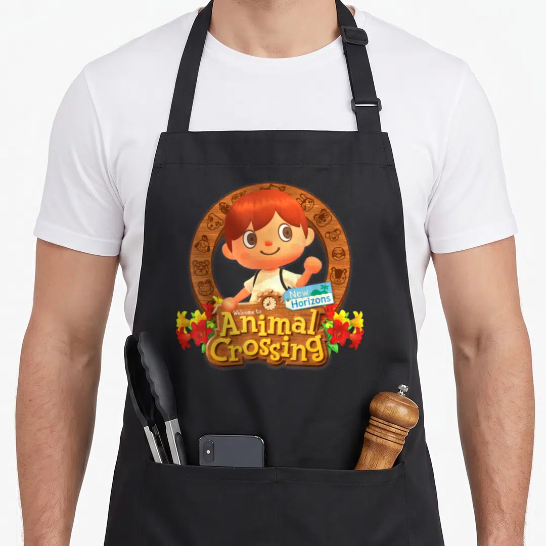 Fall animal apron - Waving cartoon person in circular wooden frame with Welcome to Animal Crossing New Horizons text — shown on a black cotton canvas apron against a white background