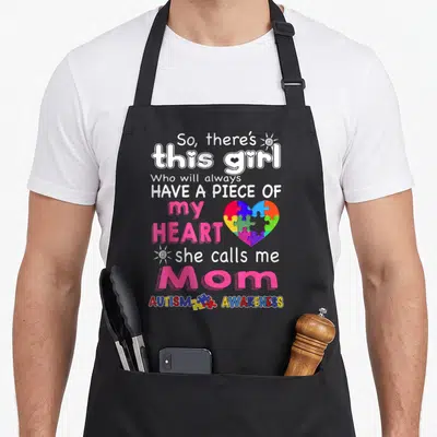 She special needs mom apron - Stacked text So there's this girl with rainbow puzzle heart and sun icons — shown on a black cotton canvas apron against a white background