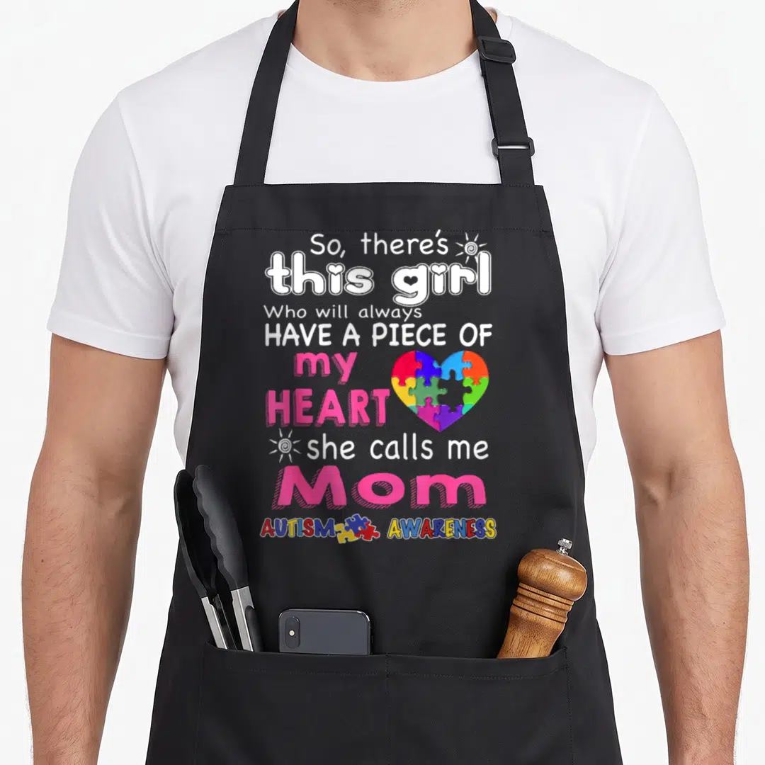 She special needs mom apron - Stacked text So there's this girl with rainbow puzzle heart and sun icons — shown on a black cotton canvas apron against a white background