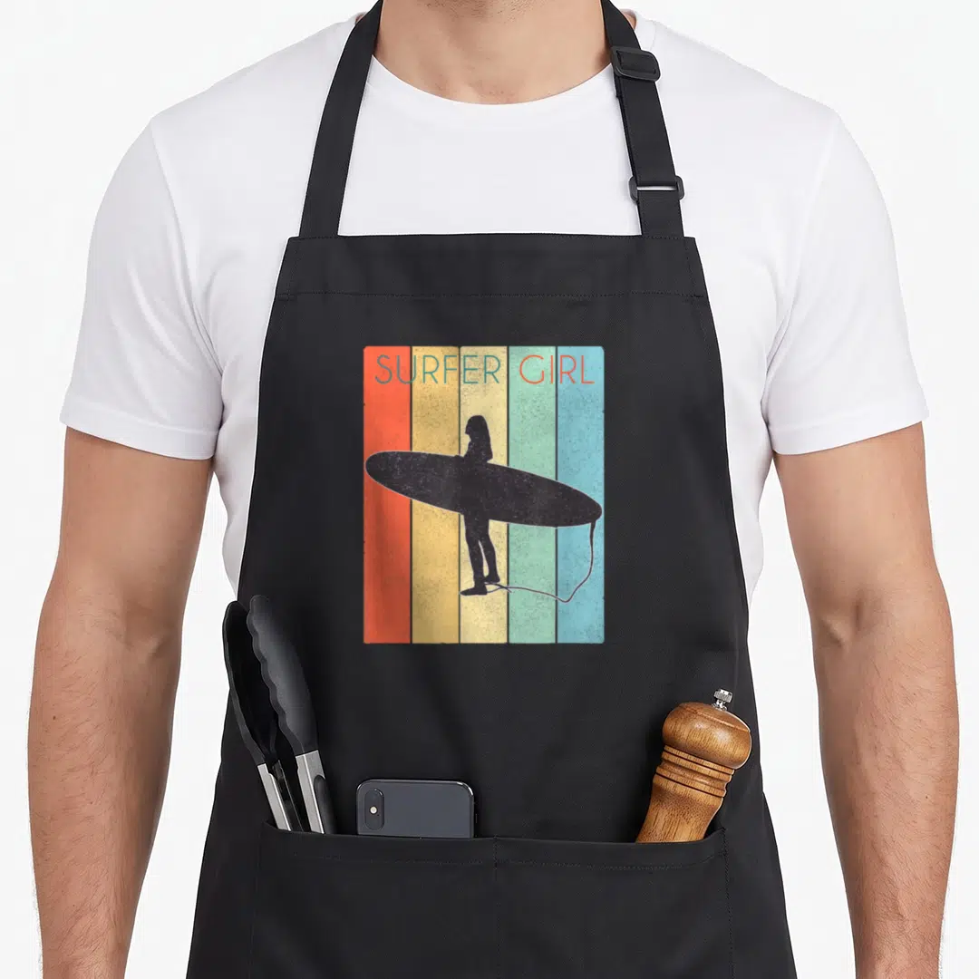 Surf surfer apron - SURFER GIRL text above silhouette holding board against five vertical colored stripes — shown on a black cotton canvas apron against a white background